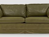 a green leather couch with two pillows on it