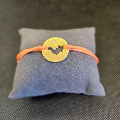 un gros plan sur un petit oreiller sur lequel est posé un bracelet jaune et orange