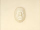 a white sculpture of a man ' s face in a gold frame