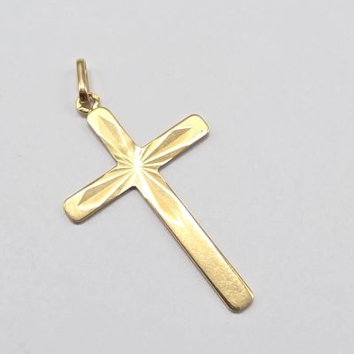 une image représentant un pendentif en forme de croix en or sur fond blanc