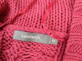 close up of a red knitted sweater with a name tag on it