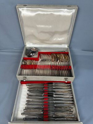 des couverts dans un coffret en argent avec des poignées rouges sur fond bleu