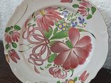 two plates with flowers painted on them sitting on a table