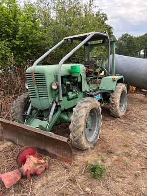 un tracteur qui est à l'arrêt dans la terre, près d'un tuyau