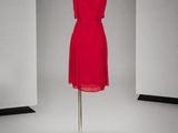 une robe rouge posée sur un pied de mannequin dans une pièce