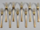 six forks are arranged in a row on a white surface