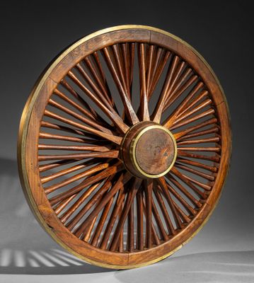 an antique wooden wheel with a metal spoke on a white surface