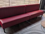 a red couch sitting in front of a window next to a wooden table