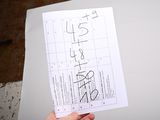 a person holding up a piece of paper with numbers on it