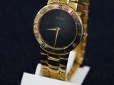 an image of a close up of a gold wrist watch on a stand