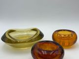 three different colored glass bowls sitting next to each other on a white surface