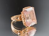 an image of a ring with a pink stone on a reflective surface