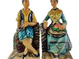 pair of ceramic figurines of a woman and a man sitting on a bench