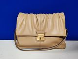 un sac à main en cuir beige posé sur une table blanche