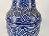 a blue and white vase with a lid on a white surface