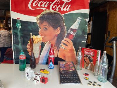 une table sur laquelle se trouvent une publicité pour Coca-Cola, une calculatrice, une calculatrice, une calculatrice, une calculatrice et une