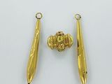 pair of gold plated earrings and a gold bead on a white surface