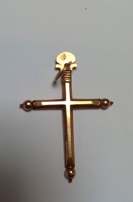 une croix dorée posée sur une table blanche sur laquelle se trouve une croix dorée