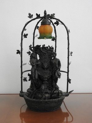 une statue posée sur une table avec une lampe