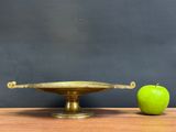 an apple sitting next to a brass plate on a wooden table