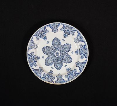 assiette bleue et blanche ornée d'un motif floral sur fond noir