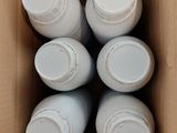 six white bottles in a cardboard box on a table