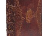 un vieux livre à la couverture brune posé sur une surface blanche