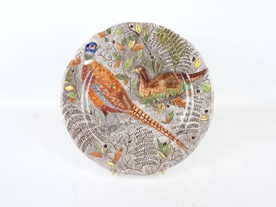 une assiette sur laquelle est représenté un oiseau, sur un fond blanc