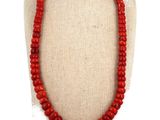 a close up of a necklace with red beads on a mannequin
