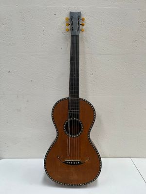 une image représentant une petite guitare en bois posée sur une surface blanche