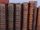 many old books lined up in a row on a shelf
