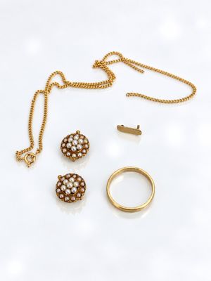 un gros plan d'un collier, d'une bague et d'une boucle d'oreille posés sur une surface blanche