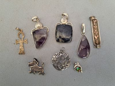 several silver and amethorate pendants and charms on a table