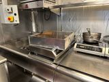 plan de travail en acier inoxydable dans une cuisine professionnelle, avec une poêle posée sur la cuisinière