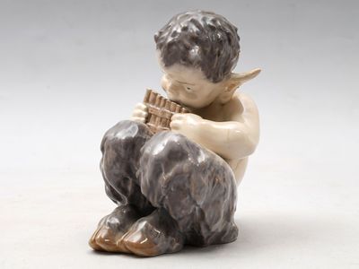 une petite figurine représentant un garçon jouant de la flûte