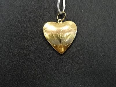 un gros plan d'un pendentif en forme de cœur doré posé sur une surface en cuir noir