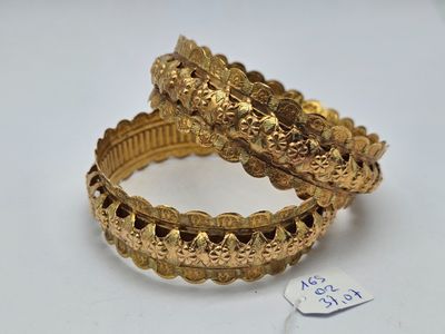 une paire de bracelets en or posés sur une surface blanche, avec une étiquette de prix