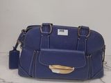 sac à main en cuir bleu posé sur une surface en marbre, sur fond blanc