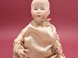 an old doll sitting on a red surface with a pink background