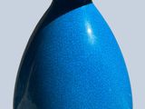 un vase bleu orné d'un couvercle doré, posé sur un socle