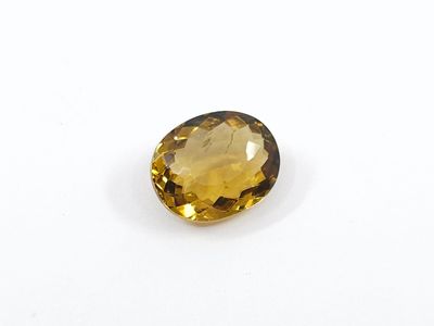 a yellow sapphire stone on a white surface