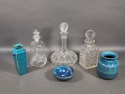 five glass bottles and a vase sitting on a table
