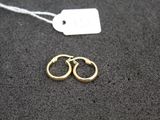 two pairs of gold hoop earrings on a black surface with a price tag