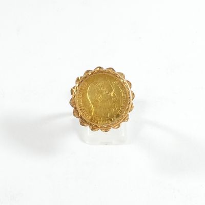 un gros plan d'une bague en forme de pièce d'or posée sur une surface blanche