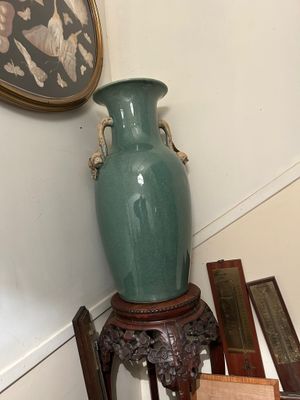 un vase vert posé sur une table à côté d'une chaise