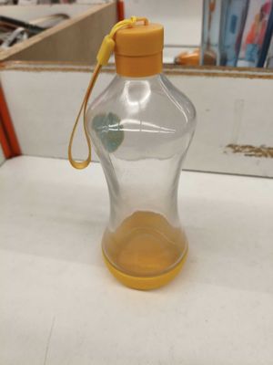 une bouteille d'eau en verre avec une poignée jaune posée sur une table