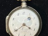 une montre de poche en argent avec un cadran blanc sur fond noir