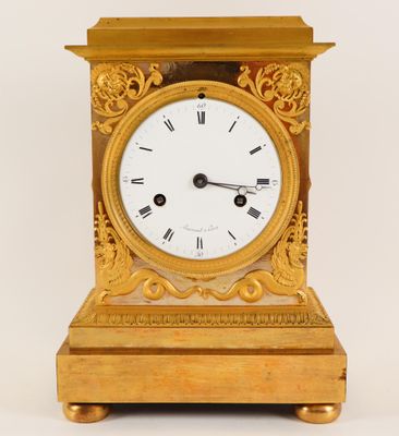 a gold clock with roman numerals on the face