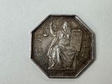 a silver coin with a lady sitting on top of it