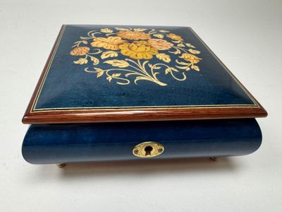 a blue box with gold flowers on it on a white surface
